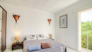 A bedroom with a bed, two bedside tables, a nightstand, a window with a view of greenery, and wall-mounted lamps. - Fontanaccia - PERI PLAIN (PLAINE DE PERI)