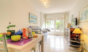 A room with a dining table, chairs, a sofa, a television, and a lamp. - Fontanaccia - PERI PLAIN (PLAINE DE PERI)