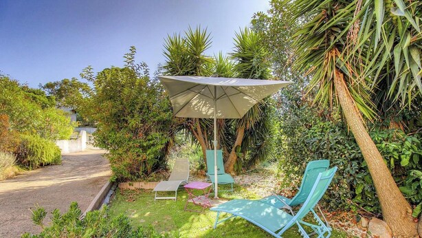 A garden with a patio area, including a table, chairs, and a large umbrella. - Fontanaccia - PERI PLAIN (PLAINE DE PERI)