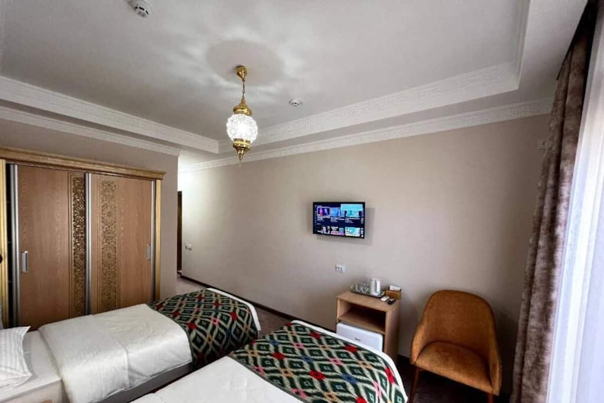 Una habitación de hotel con dos camas, televisión, armario, silla y escritorio.