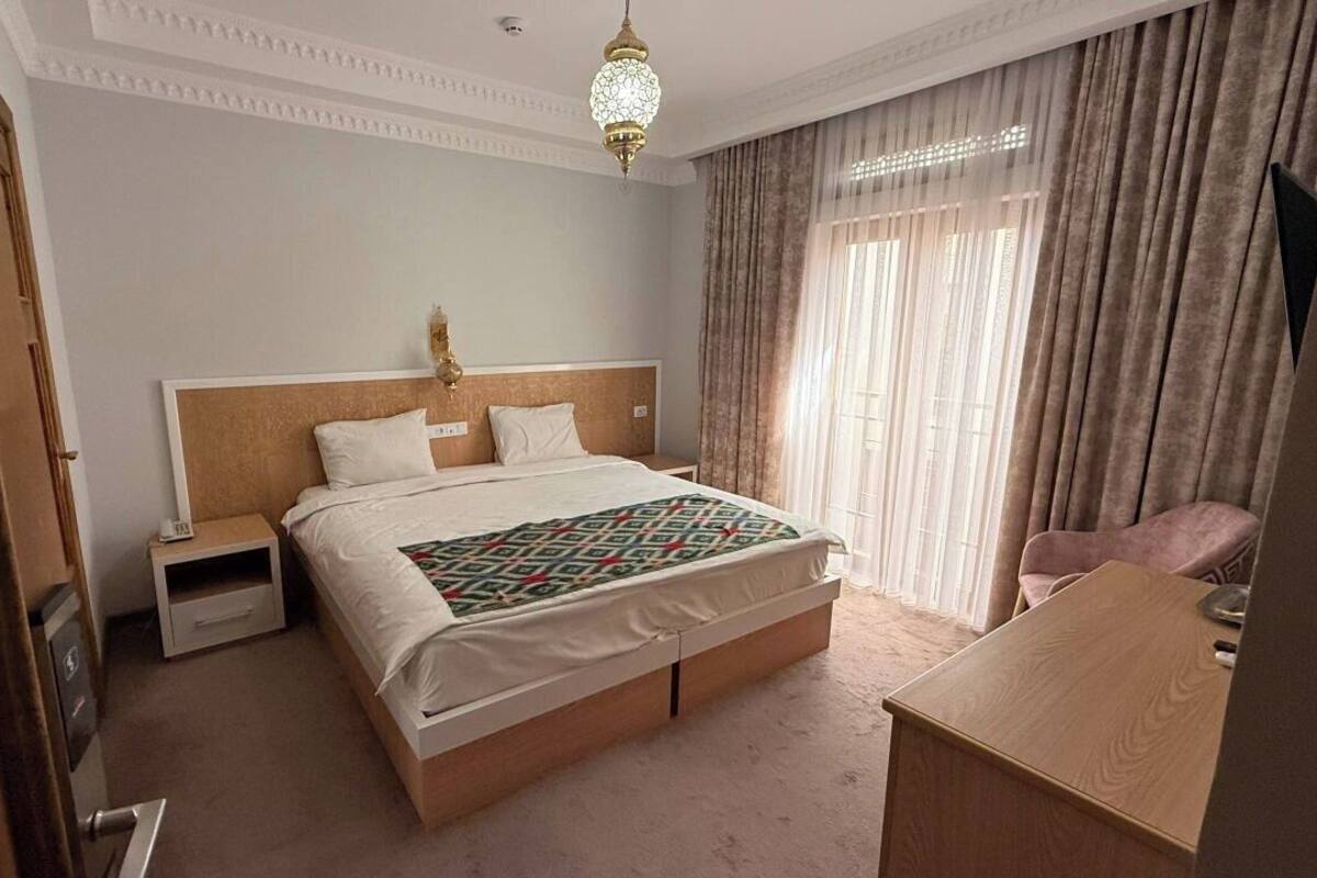 Una habitación de hotel con una cama grande, una mesita de noche, un escritorio y una silla.