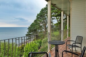 Ein Balkon mit Tisch und Stühlen mit Blick auf Strand und Bäume.