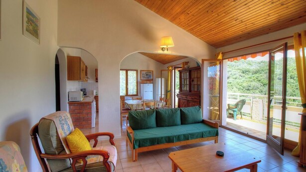 Una sala acogedora con sofá, sillas, una mesa de comedor y una cocina al fondo.
