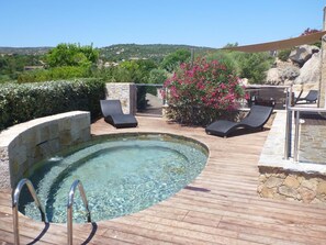 Ein Poolbereich mit klarem Pool, Liegestühlen und Blick auf die Landschaft.