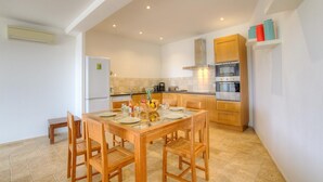 Een moderne keuken met houten kasten, een inbouwoven en een eethoek met een houten tafel en stoelen.