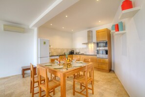 Eine moderne Küche mit Holzausstattung, einem eingebauten Backofen und einem Essbereich mit Holztisch und Stühlen.