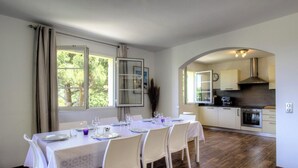 Un comedor con una mesa dispuesta para cuatro personas, una cocina con electrodomésticos modernos y vistas a zonas verdes.