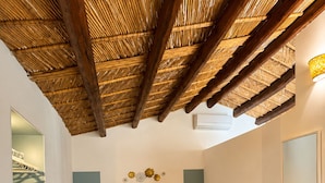 A bedroom with a bed, bedside tables, a bench, a mirror, and a ceiling with wooden beams. - Borgo degli Ulivi – An Authentic Sicilian Countryside Getaway with a Private Pool (Roccazzo)
