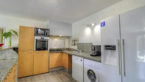 Angolo cottura compatto con microonde, forno, macchina da caffè, lavastoviglie e frigorifero.