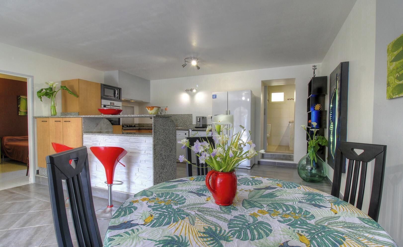 A modern kitchen with white cabinets, a granite countertop, and a dining area with a table set for two.