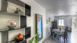 En matplats med ett bord och stolar, en vägghylla med dekorativa föremål och en stor, abstrakt målning.