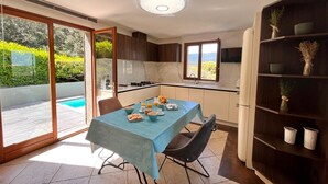 Cozinha moderna com área de jantar, vista para a piscina e estante embutida.