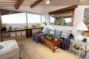 Ein gemütliches Wohnzimmer mit großem Fenster, einer Couch, einem Couchtisch und einem Schreibtisch mit Stauraum.