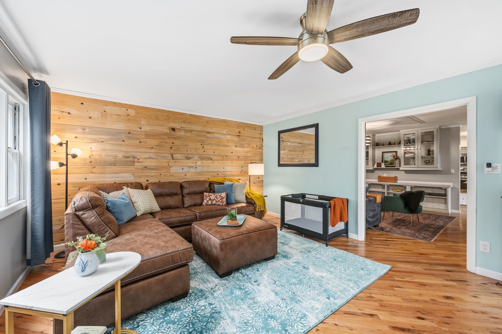 A living room with a sectional sofa, ottoman, and a ceiling fan.