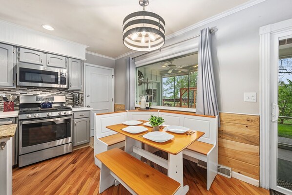 A modern kitchen with stainless steel appliances, a wooden dining table, and a bench. - Sandstone Hollow King Suite, Office, Fenced Yard (Fort Collins)