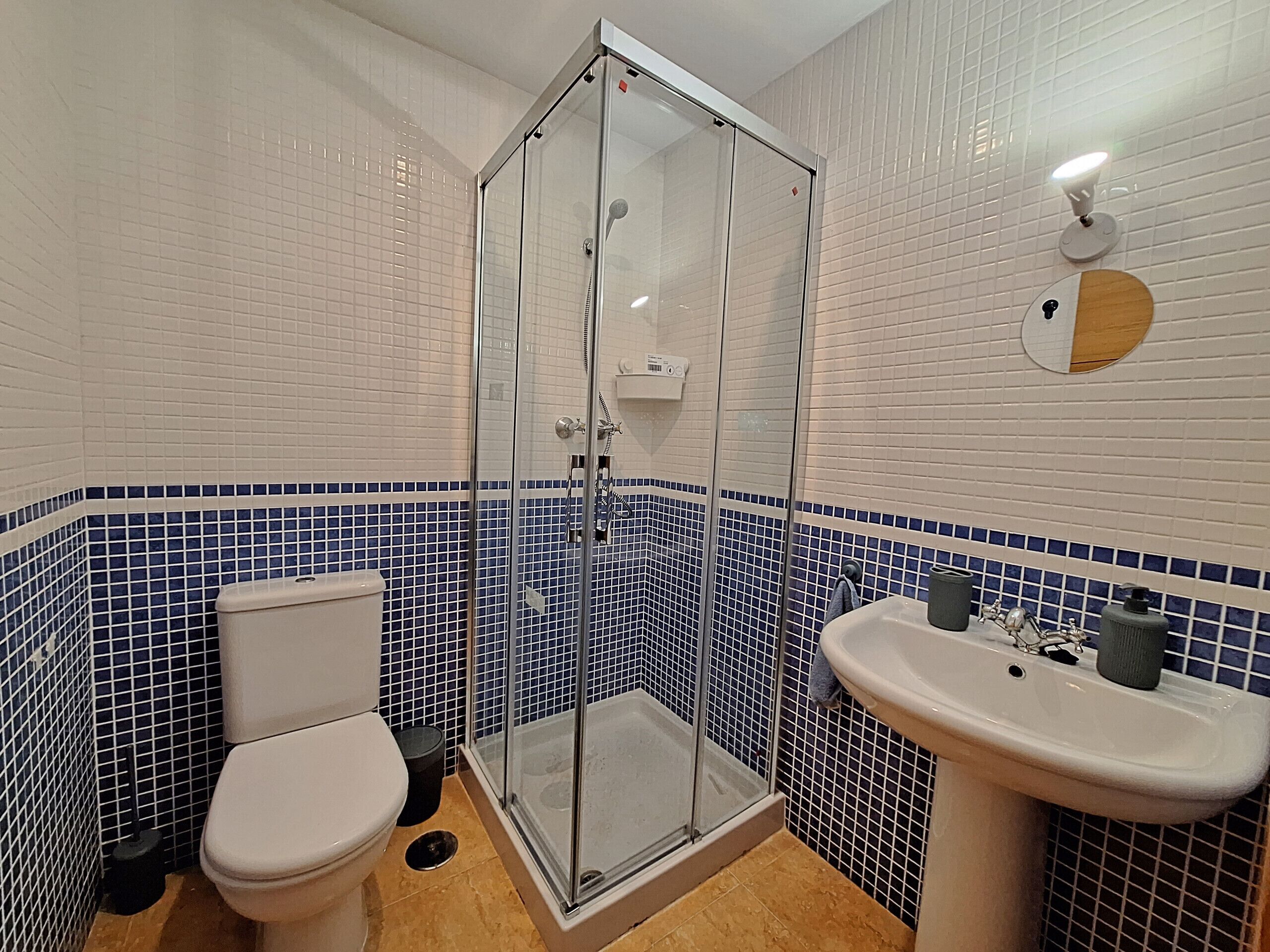 A bathroom with a toilet, a glass-enclosed shower, and a sink.