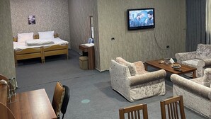 Habitación de hotel con cama, televisor, sofá, mesa de centro y escritorio.