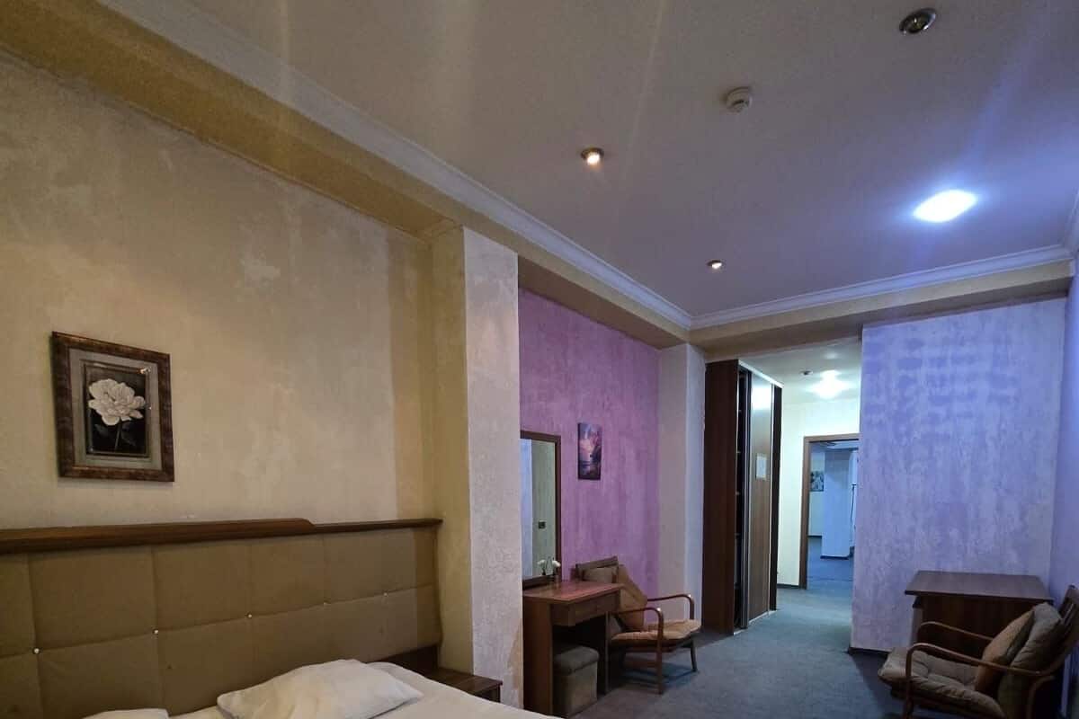 Hotellihuone, jossa on suuri sänky, työpöytä, tuoli ja pieni pöytä.