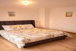 Une chambre à coucher avec un lit, une tête de lit et deux tableaux accrochés au mur.