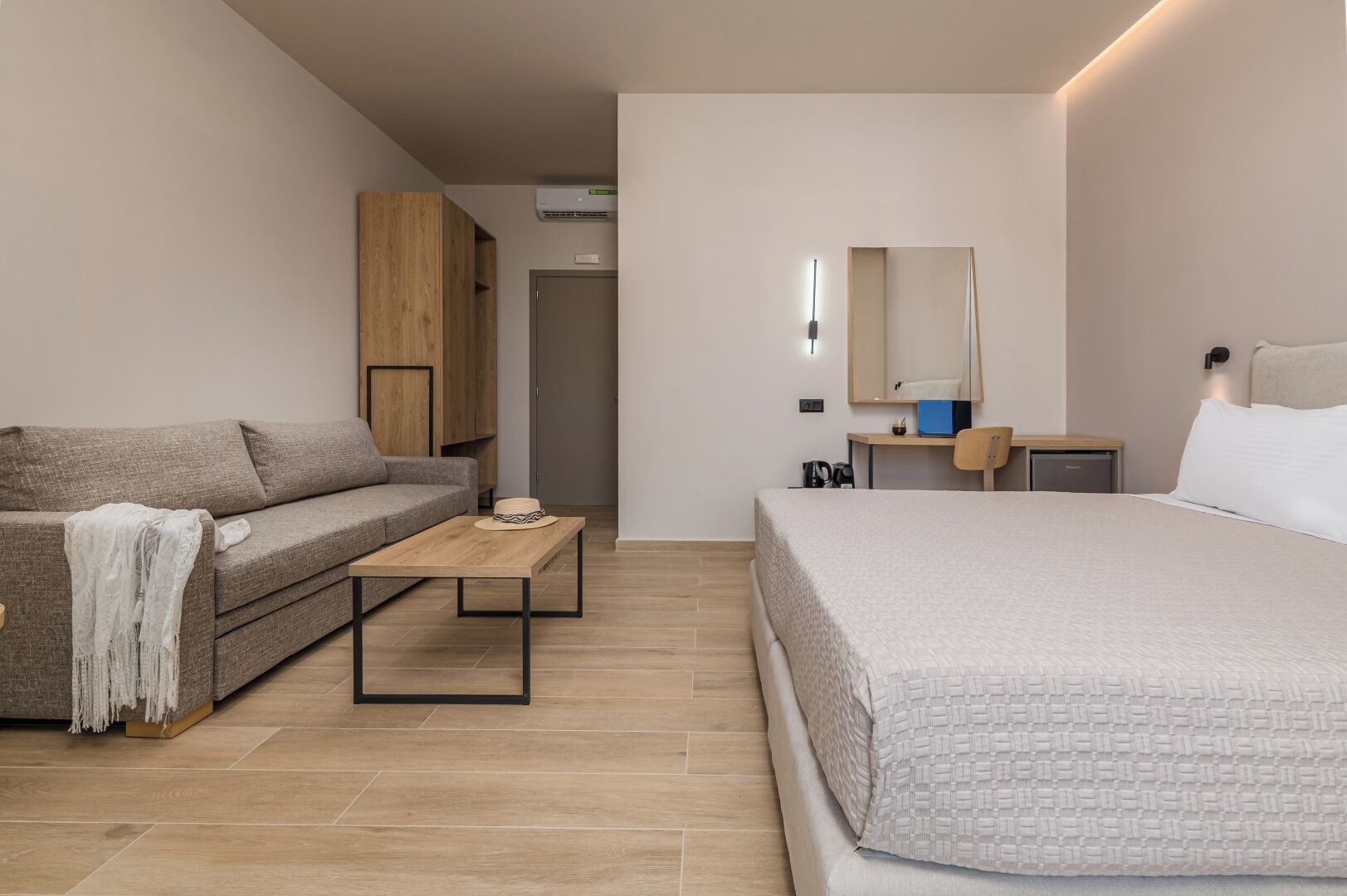 Una habitación de hotel moderna con una cama, un sofá, un escritorio y un armario.