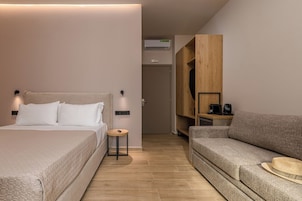 Una habitación de hotel moderna con una cama, un sofá, una mesita redonda y un armario.