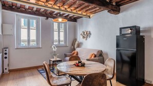 A modern kitchen with a black refrigerator, wooden dining table, and chairs, a sofa, and a ceiling with exposed beams. - Appartamento Petri7 - Affitti Brevi Italia (Lucca)