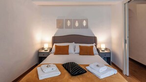 A neatly made bed with white linens, a brown headboard, and a nightstand with a lamp. - Appartamento Petri7 - Affitti Brevi Italia (Lucca)