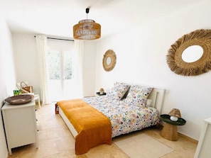 A bedroom with a bed, a bedside table, a lamp, and a window with curtains.