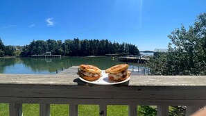 Une terrasse en bois avec une assiette de sandwichs et une vue sur un lac et une forêt.