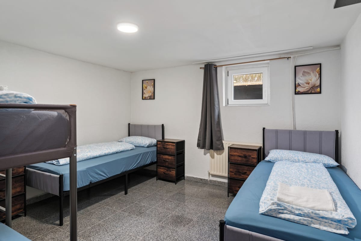 Un dormitorio con dos camas individuales, un ventanal con cortina y un radiador.