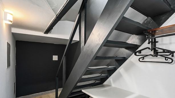 A modern interior with a staircase, a bench, and a wall-mounted hanger.