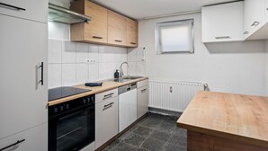 A kitchen with white cabinets, a wooden countertop, a built-in oven, and a window with blinds.