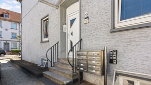 A building entrance with a white door, a staircase, and a mailbox.