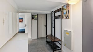 A hallway with a bench, a door, and a wall-mounted light fixture.