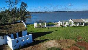 Una casa con techo de paja, piscina y vistas a un lago.