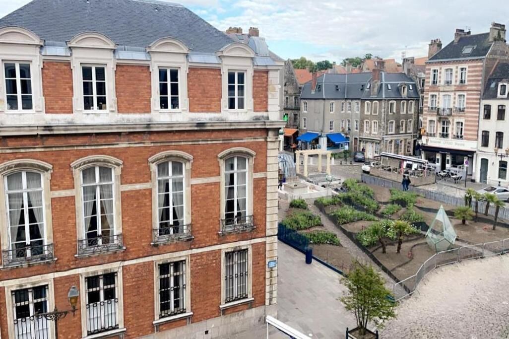 A historic building with a brick facade, large windows, and a courtyard with greenery.