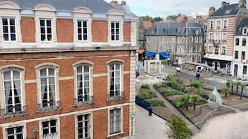 A historic building with a brick facade, large windows, and a courtyard with greenery.