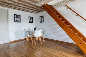 Un coin repas avec une table et des chaises, un escalier et des tableaux encadrés au mur.