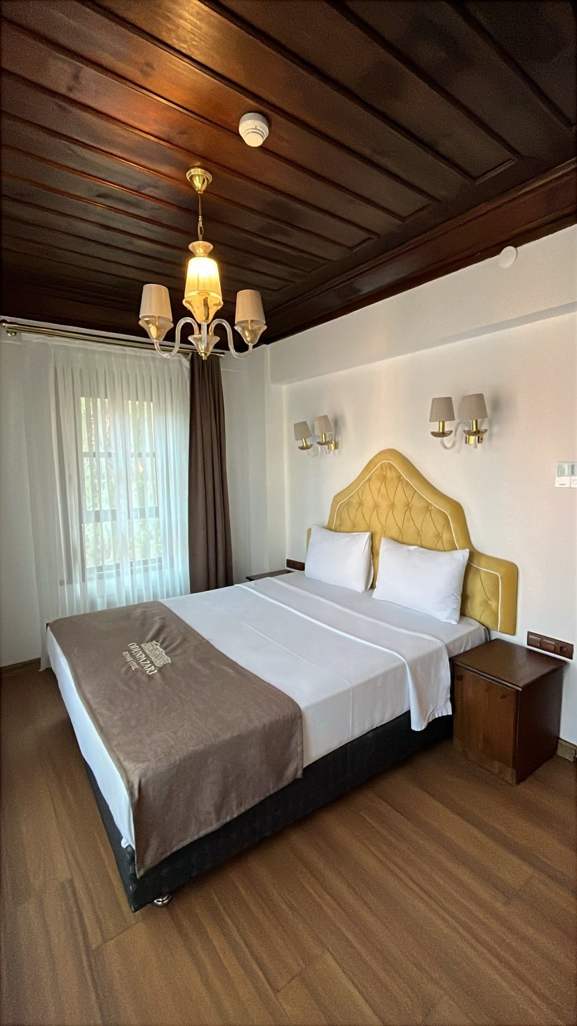 Une chambre d’hôtel avec un grand lit, un plafond en bois et un lustre.
