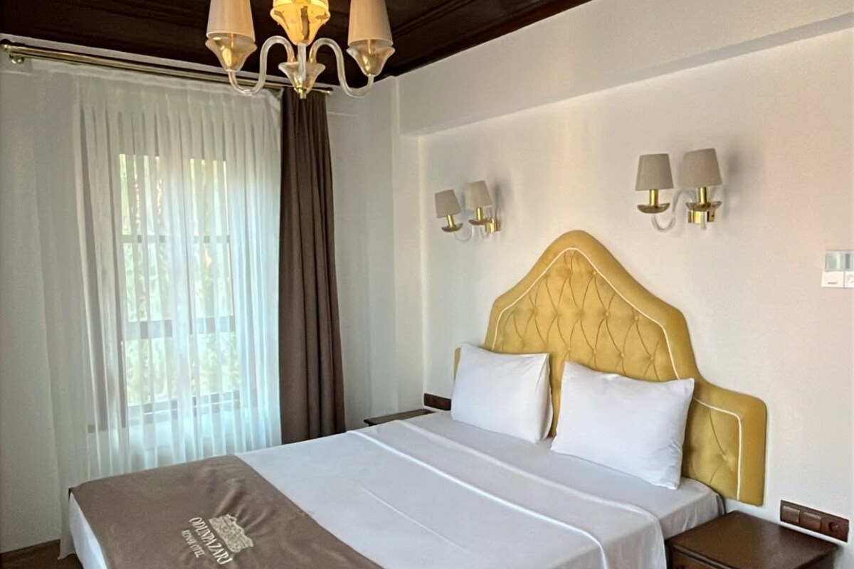 Una habitación de hotel con una cama grande, techo de madera y un candelabro.