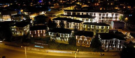 A nighttime aerial view of a residential area with multiple buildings, a clear road, and streetlights.