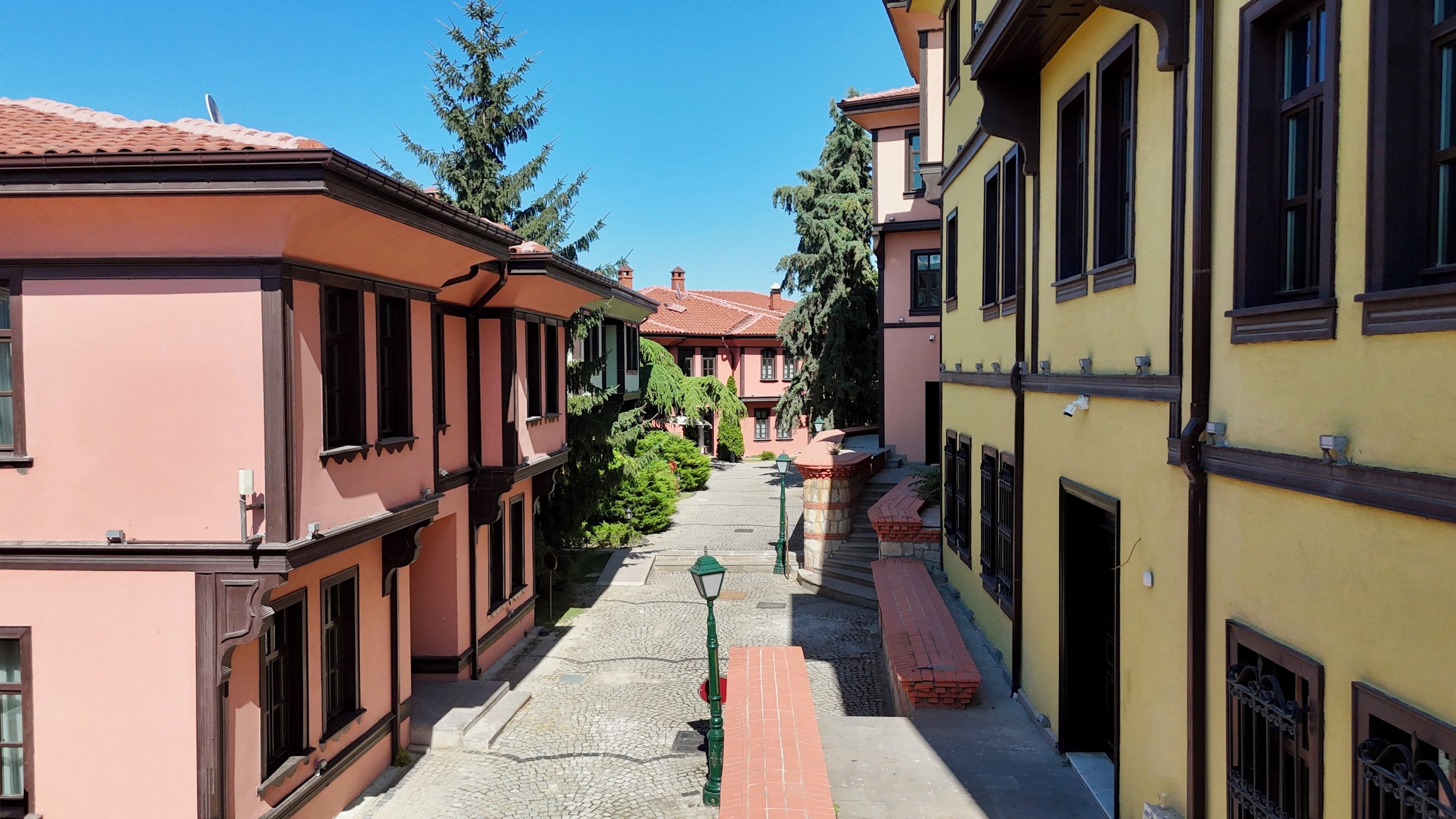Una calle estrecha bordeada de edificios tradicionales, un camino adoquinado y una farola verde.