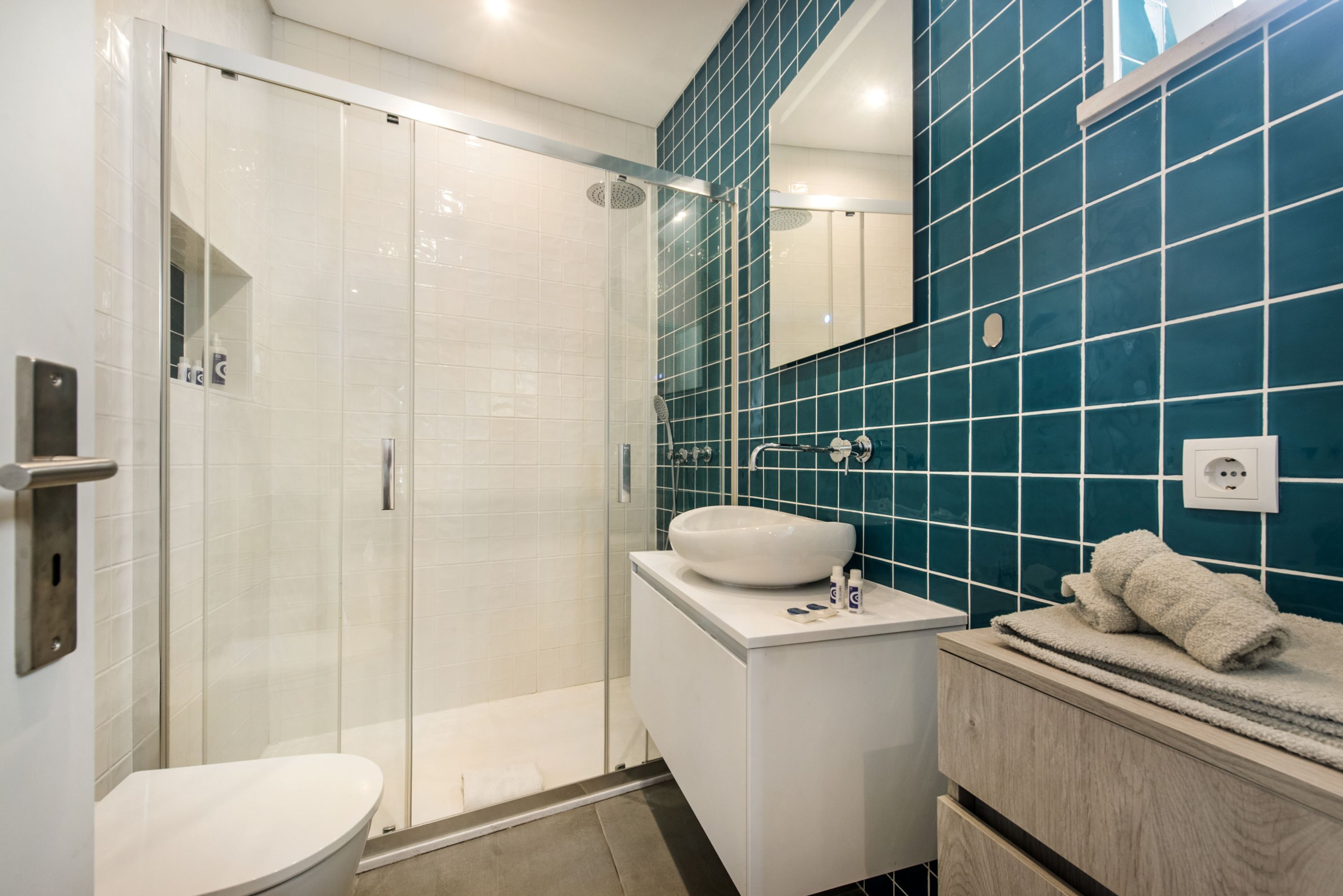 A modern bathroom with a glass-enclosed shower, a white sink, and a mirror above it.