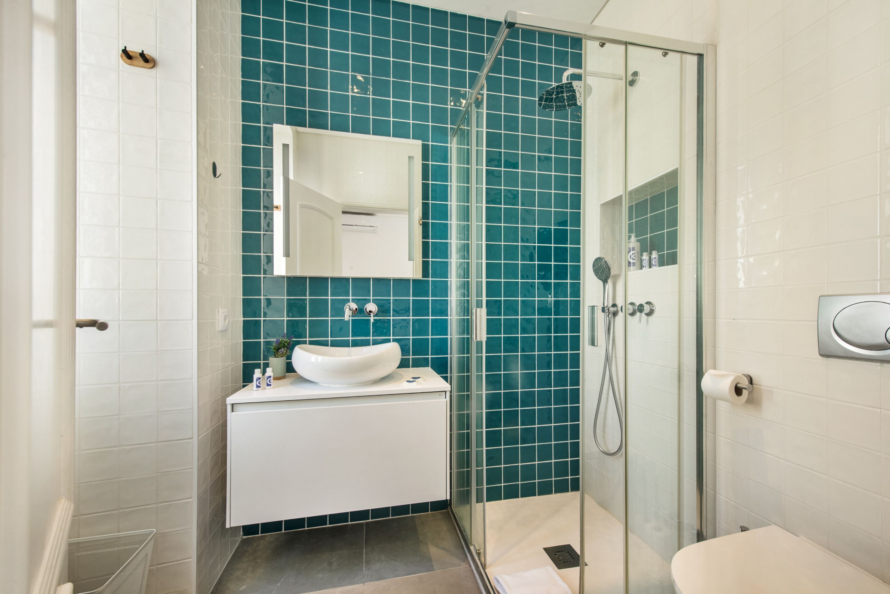 A bathroom with a glass shower enclosure, a white sink, and a mirror.