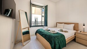 Ein Schlafzimmer mit Bett, Nachttisch und einem Fenster mit Rollläden.