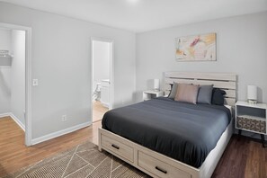 Un dormitorio moderno con una cama grande, mesitas de noche y un cuadro en la pared.