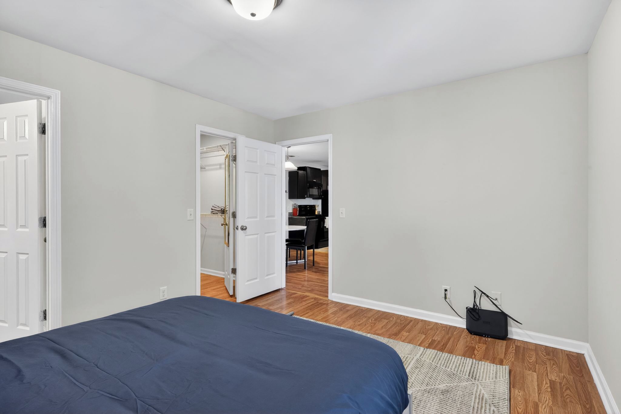 Une chambre avec un lit, une porte donnant sur une salle de bain et un couloir menant à une cuisine.