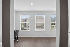 A room with three windows, a desk, and a chair.