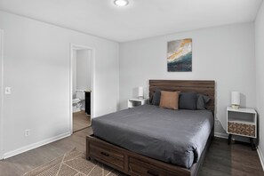 A bedroom with a bed, nightstands, a painting, and a wooden headboard.