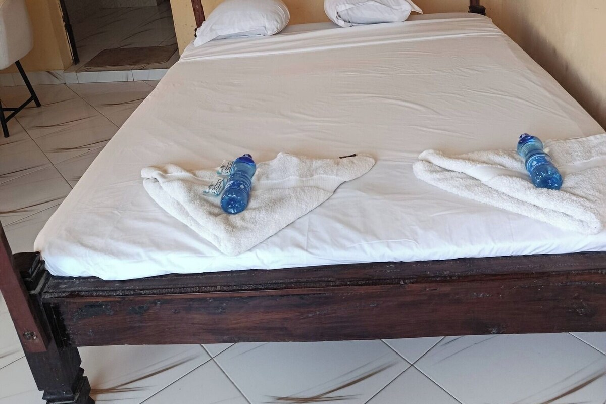 Una cama con dosel, dos almohadas y dos toallas.